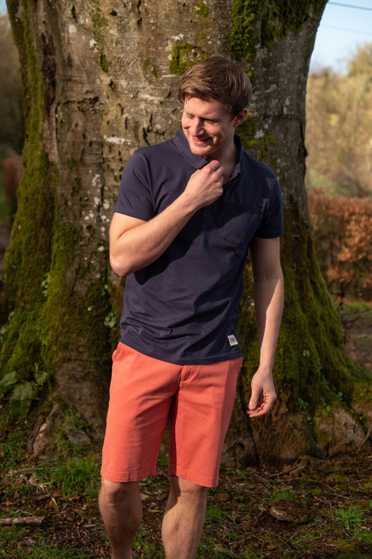 Lifestyle image of male model wearing a navy polo shirt and red chino shorts from Rupert and Buckley