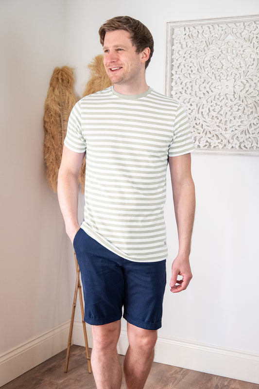 Lifestyle photograph of male model wearing blue chino shorts and green stripe t-shirt