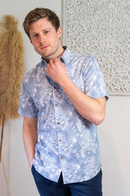 lifestyle image of male model wearing a palm print short sleeved shirt and blue chino shorts